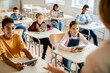 © Drazen - Multiracial group of school kids using touchpads and listening to their teacher during computer class.