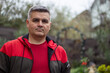 © MakZin - Portrait of a man 40-50 years old, gray-haired, swarthy. Serious look. Big eyebrows. Red jacket. Looking at the camera