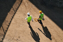 Directly Above View Of Builders In Hardhats And Green Waistcoats Working At Construction Site
