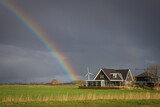 Fototapeta Tęcza - Holenderska farma, uroczy domek wśród pól, w tle zachmurzone niebo z tęczą.