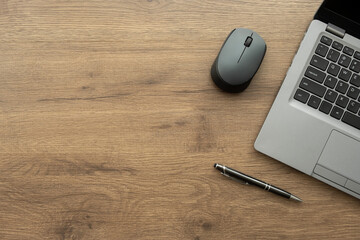 Wood office desk table with laptop computer, black mouse and pen. Top view with copy space, flat lay.