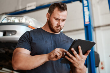 Wall Mural - Open the app to find a reliable and trustworthy mechanic near you. Shot of a mechanic using a digital tablet while working in an auto repair shop.