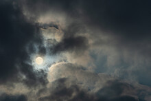 Photograph Of Full Moon Between Heavy Clouds. Dark Cloudy Gloomy Sky.