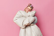 © WHstudio Leushin N - Pleased young European woman sees sweet dreams tilts head holds blanket prepares for party makes hairstyle applies hair rollers and beauty patches isolated over pink bakground. Time to have rest