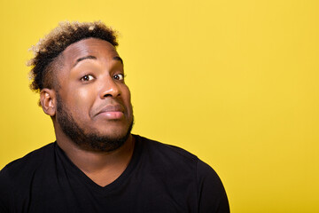 Wall Mural - A dark-skinned, handsome unshaven man with curly hair looks into the camera lens with a surprised look. A young man in casual clothes looks questioningly at the photographer