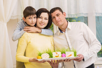 Mother, father and a son painting eggs in the kitchen 