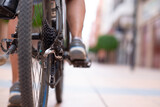Close up on the bicycle chain as a woman is pedaling on an urban street