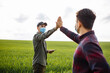© Konstantin Zibert - Farmers giving each other high-five in wheat field. Smart farm. Men in the middle of a green field inspect the harvest.