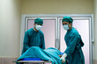 © BritCats Studio - Selective focus at face of the doctor while moving out the body of pass away patient while doctor covering face inside of the surgery operation room in the hospital. Illness and death concept.