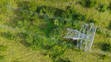 Aerial Top Down View High Voltage Steel Power Pylons In Green Field Countryside. Flight Over Power Transmission Lines. Electric Tower Line, Daylight, Summer Day