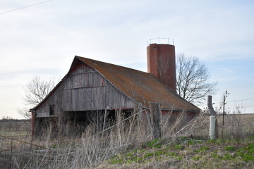 Canvas Print - Weathered Barn and a Silo in a Farm Field