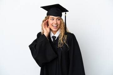 Wall Mural - Young university graduate isolated on white background listening to something by putting hand on the ear