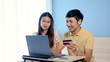 © Ekkasit A Siam - Young Asian man, couple looking at shopping, and ordering online via laptop computer, two people choosing a credit card to pay for their purchases.,online shopping.