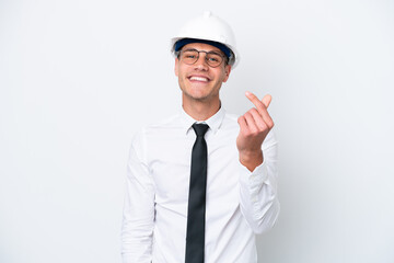 Young architect caucasian man with helmet and holding blueprints isolated on white background making money gesture