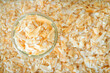 toasted crispy coconut flake in glass bowl on crispy coconut flake background.