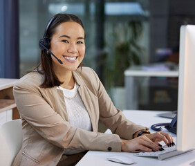 How can I make your experience a happy one. Portrait of a young woman using a headset and computer in a modern office.