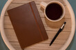 A cup of black coffee, pen and notebook lying on the wooden table