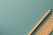 A pencil and ruler lying on the turquoise background on the right side
