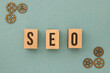 SEO - Search Engine Optimization letters made out of wood on the turquoise background with metal gears on the side
