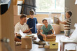 © Seventyfour - Full length portrait of happy family with two children moving into new house and unpacking boxes together