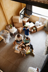 Wall Mural - Top view shot of family with two children unpacking boxes together while moving house, copy space