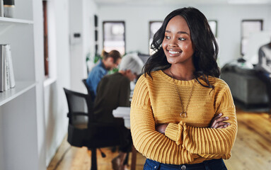 Canvas Print - Shes thinking positive thoughts. Cropped shot of an attractive young businesswoman looking thoughtful while standing with her arms folded in the office.