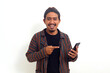 Happy asian man in javanese traditional costume standing while pointing at his phone.