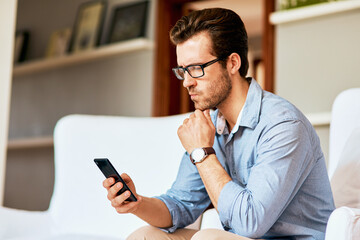 Poster - Maybe its time to switch to a new network.... Shot of a handsome young man looking confused while using a cellphone at home.