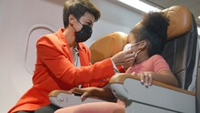 Mother Helping Her Daughter Curly Hair Girl Wearing Face Masks For Protection Covid-19 Virus Outbreak Situation While Traveling On Airplane