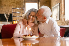 Happy Senior Man Embracing Woman Celebrating Birthday In Boutique Hotel