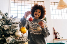 Happy Woman Holding Christmas Bauble In Hand At Home
