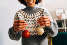 Smiling Woman Holding Christmas Baubles In Hand At Home