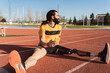 © Westend61 - Smiling athlete holding mobile phone sitting on running track