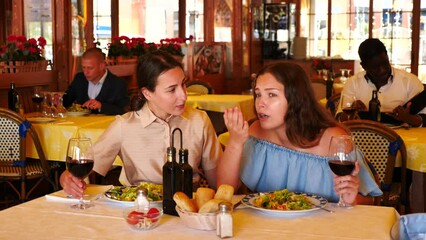 Wall Mural - Girl complains to her friend at a table in a restaurant. High quality 4k footage