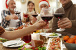 Family clinking glasses of wine at festive dinner, focus on hands. Christmas celebration