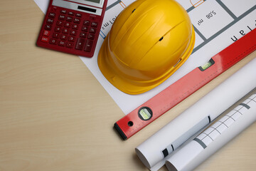 Wall Mural - Construction drawings, safety hat, calculator and bubble level on wooden table, flat lay. Space for text