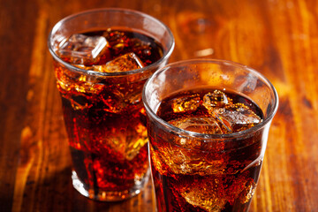 Wall Mural - glass of cold cola soft drink with ice on wooden background