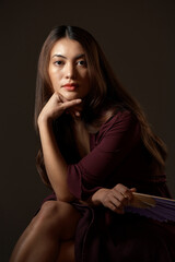 Wall Mural - Its a matter of tradition. Cropped portrait of an attractive young woman posing with a fan in studio against a grey background.