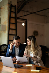 Wall Mural - Colleagues drinking coffee in office. Businesswoman and businessman discussing work in office.