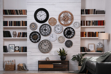 Wall Mural - Stylish room interior with console table, comfortable sofa and collection of different clocks on white wall