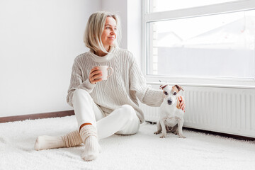 Relaxed, serene adult woman drinking cup of coffee on the sofa in the living room