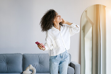 Carefree joyful african american girl jumping dancing alone moving to rhythm in living room, happy african American young woman have fun enjoying listening to music, entertain on weekend at home