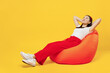 © ViDi Studio - Full size body length young girl woman of Asian ethnicity 20s years old wears casual clothes sit in bag chair hands folded under head look up rest isolated on plain yellow background studio portrait.