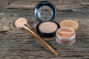 Face powder and bronzer with brush background on a wooden table.