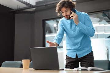 Sticker - Confused man talking on mobile phone using laptop