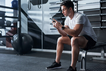 Wall Mural - Checking out the latest fitness apps. Shot of a sporty young man using a cellphone in a gym.