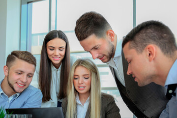 Wall Mural - Business people gathered around laptop discussing in the office