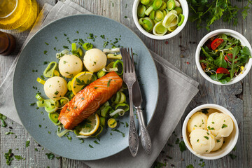 Wall Mural - Portion of fried salmon, served with mashed potatoes and cooked leek. Top view. Gray plate, wooden background.