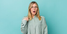Young Pretty Blonde Woman Looking Shocked And Surprised With Mouth Wide Open, Pointing To Self