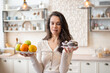 © Prostock-studio - Healthy vs unhealthy food. Doubtful woman holding plate with fruits and donuts in both hands, making choice